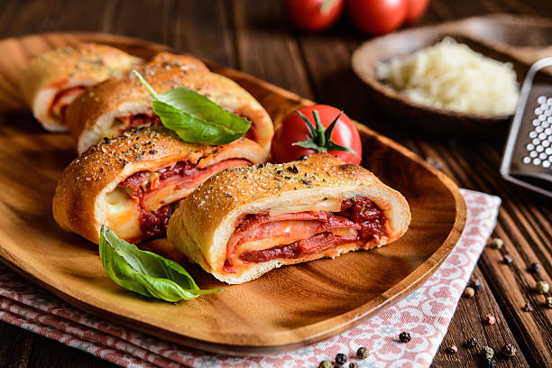 Stromboli stuffed with cheese, salami, green onion and tomato sauce Traditional Italian Stromboli stuffed with cheese, salami, green onion and tomato sauce savory food photos stock pictures, royalty-free photos & images
