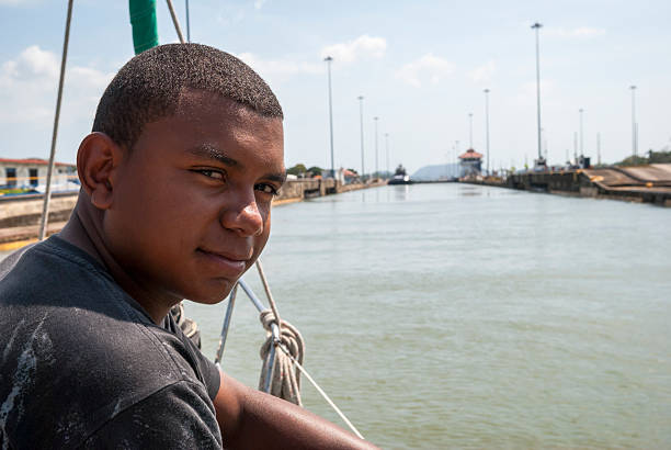 Panama Canal, Panama - December 24, 2008: A Panamanian line-handler sits at the bow of a sailboat as it enters the Pedro Miguel Locks on the Panama Canal.