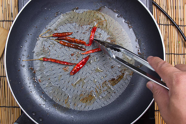 Chef frying red dried chlli in the pan