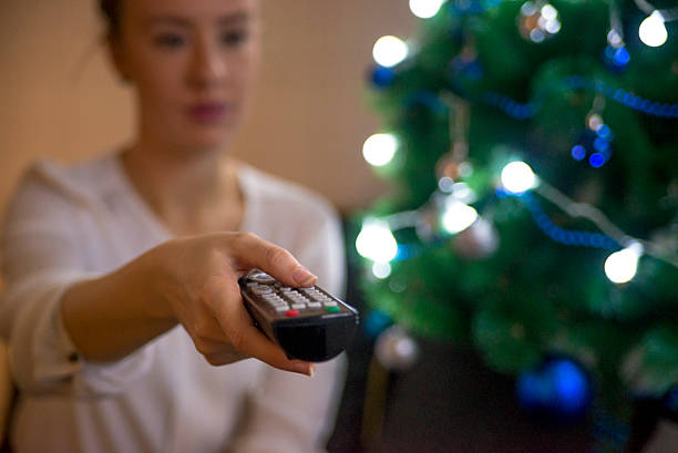 istock Young lady sitting on couch watching television on Christmas 629265808