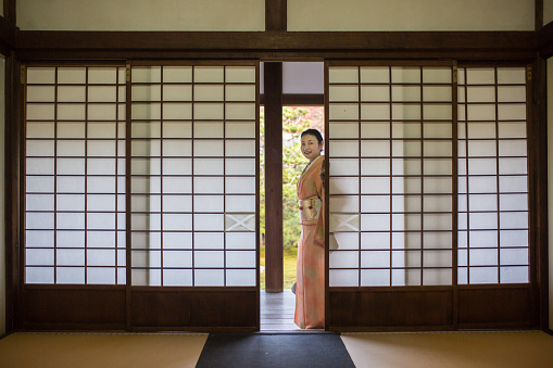 A woman in a kimono about to pass through some traditional sliding doors at a temple in Japan