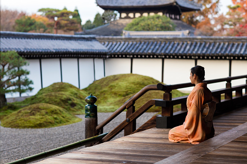 A woman wearing a a kimono walking through a temple.