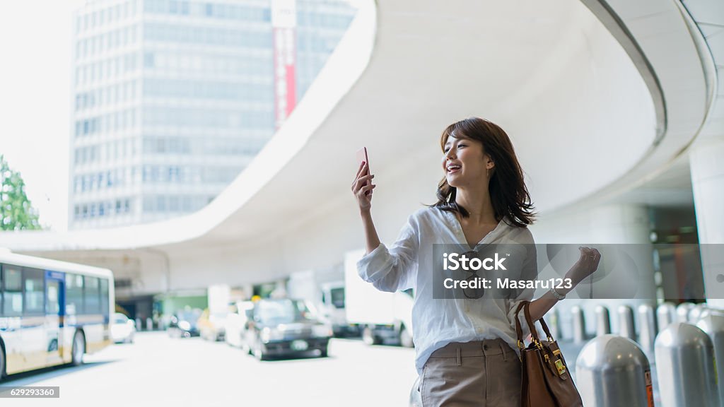 Jeune femme d’affaires regardant le téléphone portable dans une ville - Photo de Femmes libre de droits