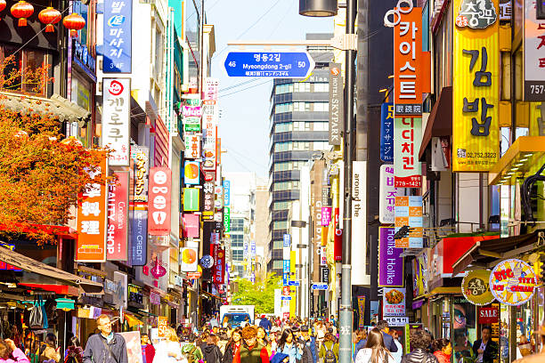 Myeongdong Crowded Shopping Street Stores Signs H Seoul, South Korea - April 17, 2015: People walking down bustling Myeongdong pedestrian shopping street surrounded by commercialism of stores, signs and crowded with tourists. Horizontal south korea stock pictures, royalty-free photos & images
