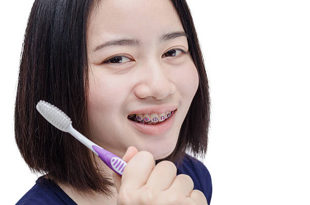 fille avec des dents corset sur blanc - smiling human teeth toothbrush moving up photos et images de collection