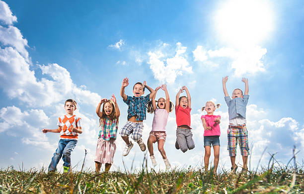 istock Group of joyful kids jumping in a meadow. 629295656