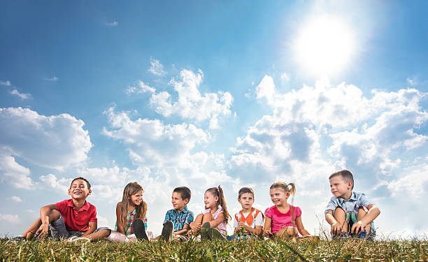 istock Large group of smiling children relaxing in grass. 629295750