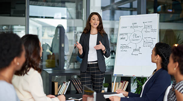 I'm happy to explain... Shot of an attractive young businesswoman giving a presentation in the boardroom voice stock pictures, royalty-free photos & images