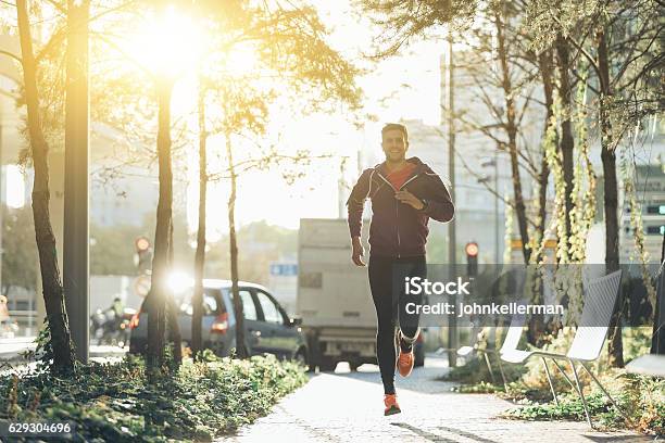 Sportler Mit Kopfhörern Läuft In Der Stadt Stockfoto und mehr Bilder von Joggen - Joggen, Stadt, Rennen - Körperliche Aktivität