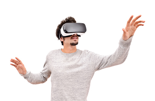 Young man using virtual reality simulator, isolated on white. 