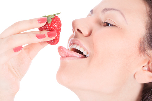 woman with red lips eating a fresh strawberry