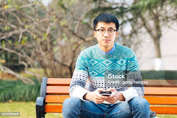 Young Asian Man Holds Mobile Phone Stock Photo - Download Image Now - Adult, Adults Only, Asian and Indian Ethnicities