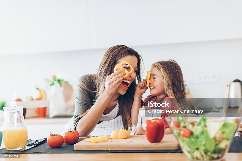 Mother and daughter having fun with the vegetables Mother and daughter having fun with the vegetables in the kitchen. Cooking Stock Photo