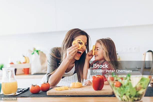 Mother And Daughter Having Fun With The Vegetables Stock Photo - Download Image Now - Cooking, Family, Child