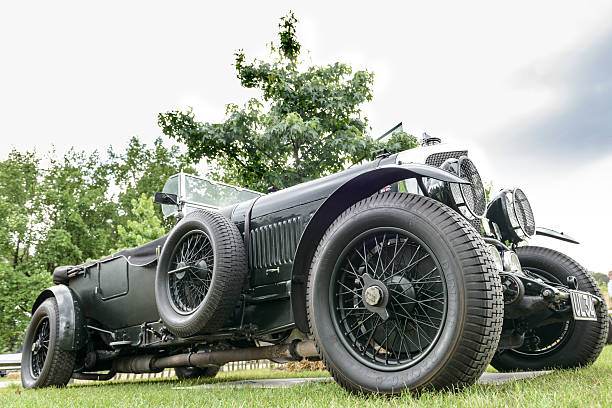 Jüchen, Germany - August 5, 2016: Vintage 1928 Bentley 6 1/2 Litre Speed Six Tourer English classic car in British racing green at a car show where people are looking at the cars. The car is on display during the 2016 Classic Days event at Schloss Dyck. The car is on display during the 2016 Classic Days at castle Dyck. The car is displayed in a field, with people looking at the cars in the background.