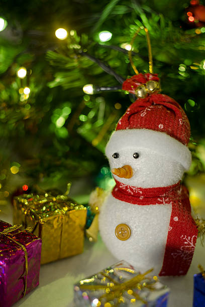 istock snowman with blurry christmas tree background and light bokeh 629358302