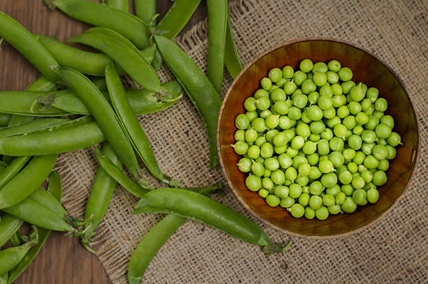 istock Pea pods in a wooden bowl on sacking.  background. Top 629358874