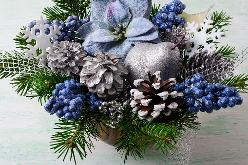Christmas background with blue silk poinsettias and glitter berries. Artificial Christmas flower arrangement with pine cones and fir branches. Holidays decoration.