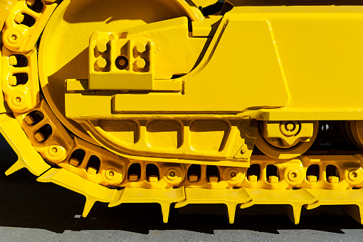 Bulldozer tracks and drive gear with sprocket mechanism, large construction machine with bolts and yellow paint coating, heavy industry, detail 