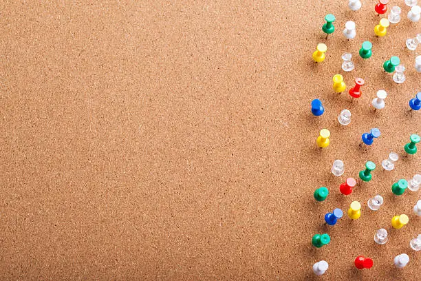 Group of thumbtacks pinned on corkboard