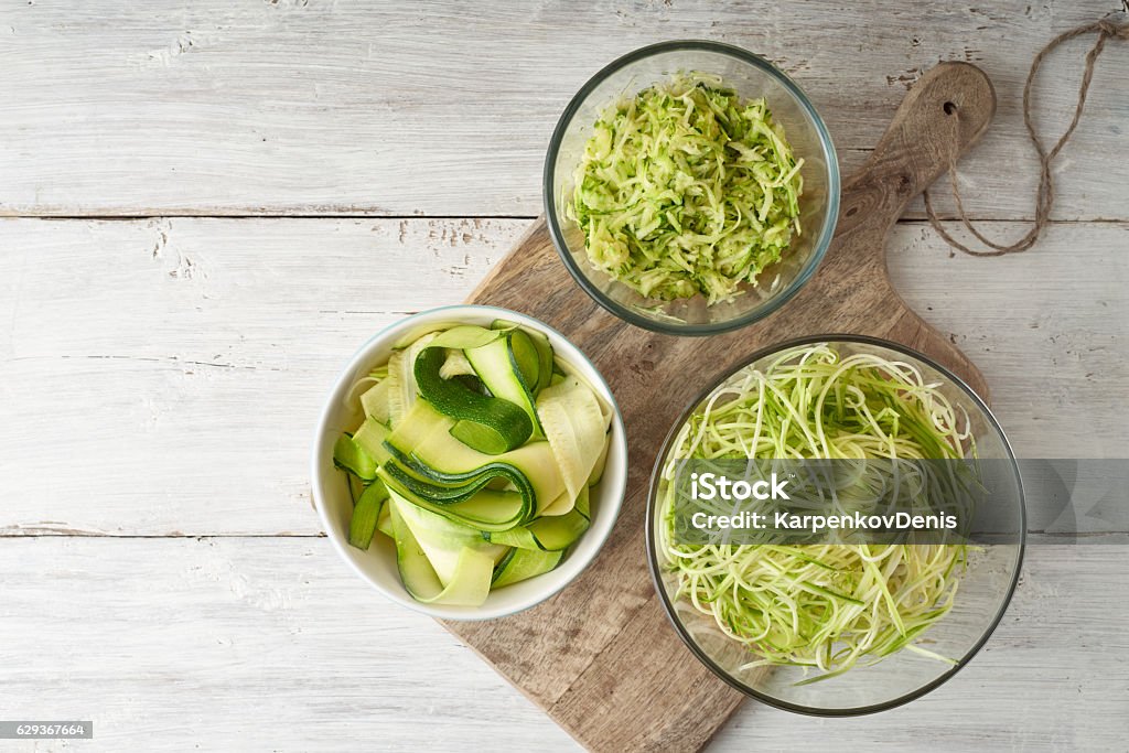 Raw zucchini noodles on the white wooden table top view Different kind of raw zucchini noodles on the white wooden table top view Zucchini Stock Photo