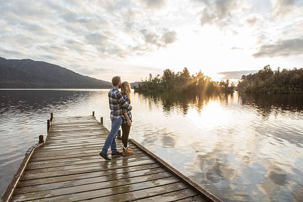 istock Young couple on lake pier watching sunset 629368528