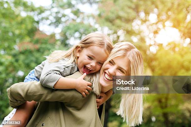 Little Girl On A Piggy Back Ride With Her Mother Stock Photo - Download Image Now - Mother, Child, Playful