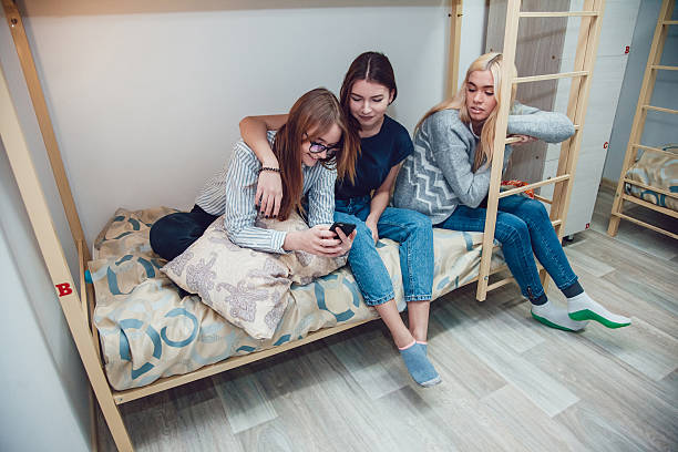 istock Beautiful girls sitting on a bed in hostel talk and 629384586