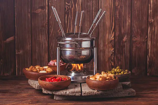 Delicious Cheese Fondue on a fork on a wooden stand