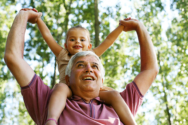 istock Older man carrying granddaughter piggyback. 629386566