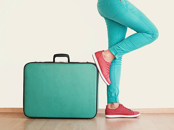 istock Young woman stands beside suitcase 629403422