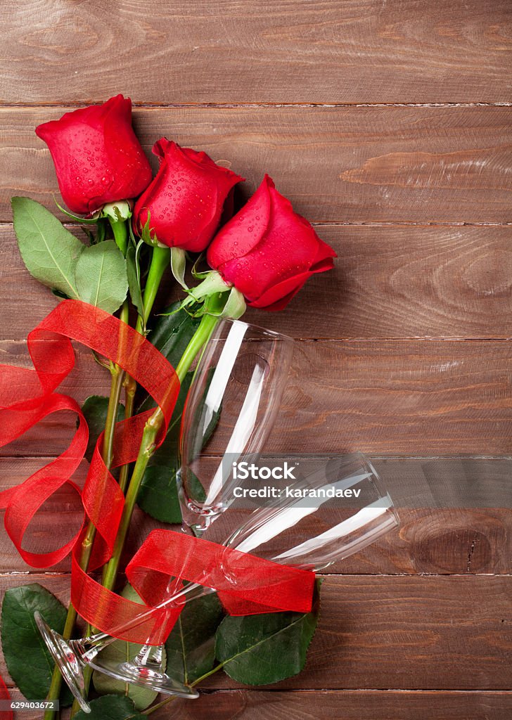 Valentines day roses bouquet and champagne glasses Valentines day roses bouquet and champagne glasses on wooden table. Top view with copy space Above Stock Photo