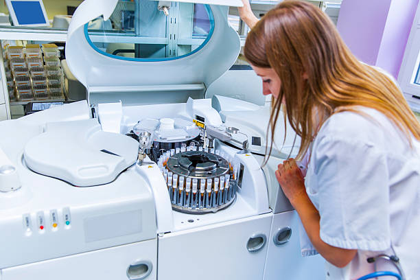 lab scientist placing test tubes with blood samples in centrifuge - santrifüj stok fotoğraflar ve resimler