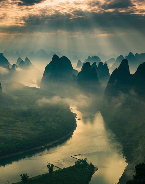 Karst mountains and river Li in Guilin/Guangxi region of China Sun beams on a misty morning on karst mountains and river Li in Guilin/Guangxi region of China yangshuo stock pictures, royalty-free photos & images