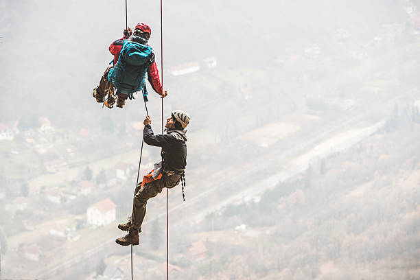 A kid wearing a harness and helmet is climbing on a rope net in a forest adventure park. Fun and courage activity for children.