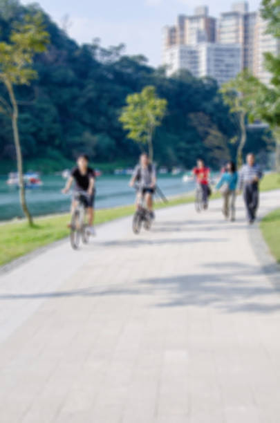 istock People riding bicycles and walking around lake 629411386