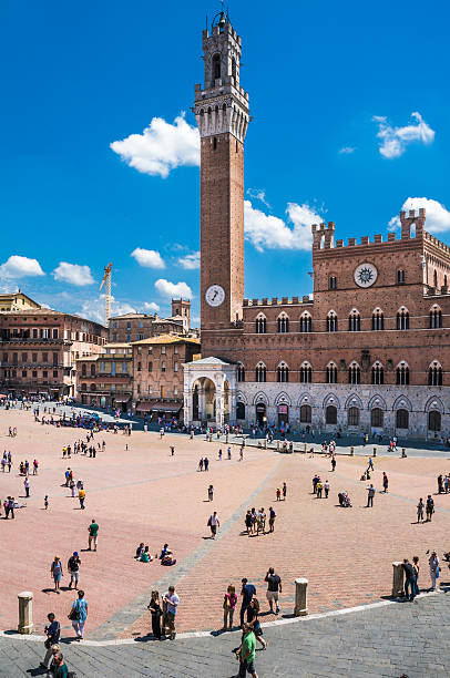 Camp Overlook Square Siena, Italy - June 4, 2011: Tourists and city residents gather at the Piazza del Campo which serves as the town common and meeting place. The Piazza's tallest building, the Torre Del Mangia (1348) is 88 meters tall. torre del mangia stock pictures, royalty-free photos & images