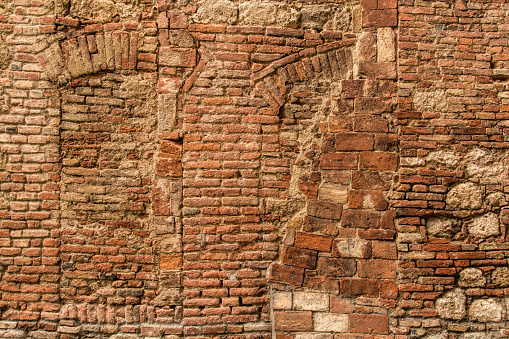 Texture of typical Italian old stone and brick wall. Traces of the pledged old windows.