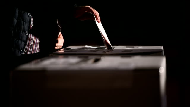 People casting votes into the ballot box