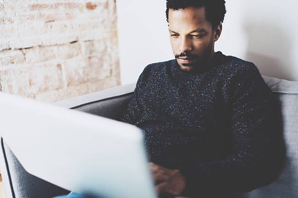 istock Closeup view of young African man using laptop while sitting 629419134