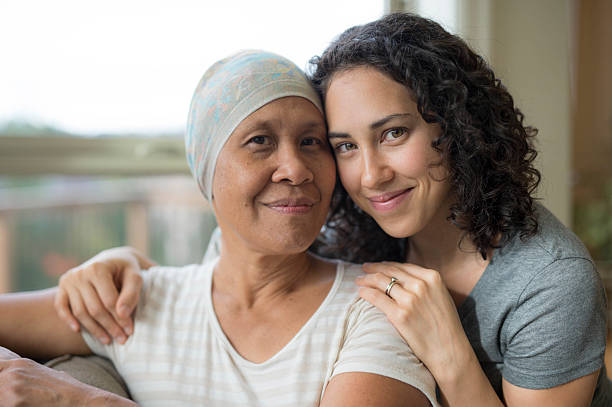Ethnic young adult female hugging her mother who has cancer Ethnic young adult female hugging her mother who has cancer cancer cell photos stock pictures, royalty-free photos & images