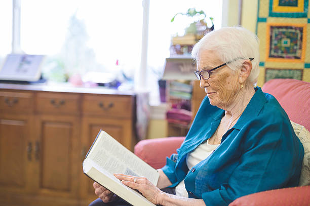 istock Cute elderly woman reading a book in longterm care facility 629420390