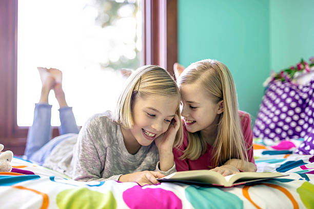 istock Young sisters reading a book together in their bedroom 629421608