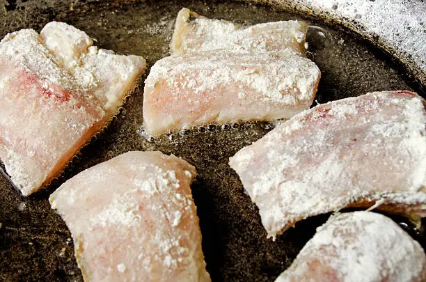 Fish fried pollack in the flour in a skillet.