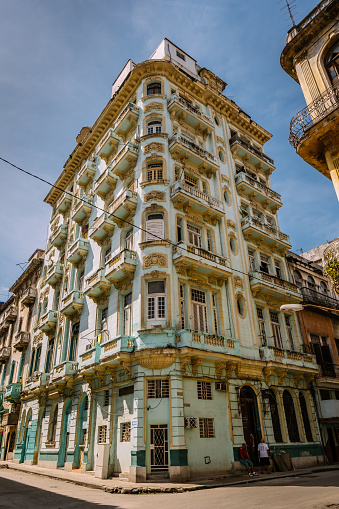 Havana, Cuba - October 8, 2016: Street corner exterior in Old Havana. People walking down the road. Rough shape facades of old colonial building on the corner. Typical scene all around old Havana, where ever you see old buildings . Variety of colours and styles. Beauty of old architecture neglected over many years with out upkeep.