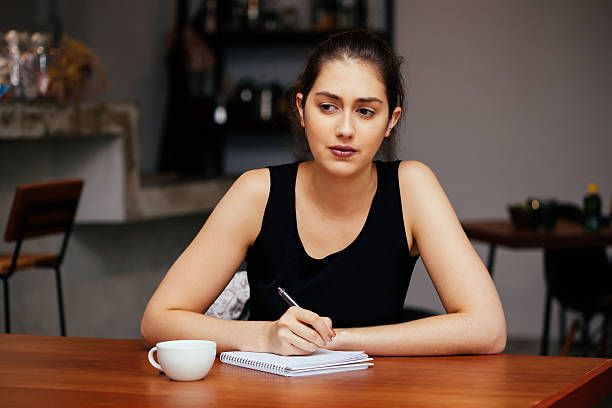 istock Young Caucasian woman thinking and writing something on notebook 629429822