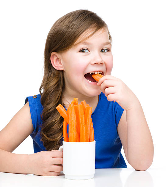 Cute little girl is eating carrot stock photo