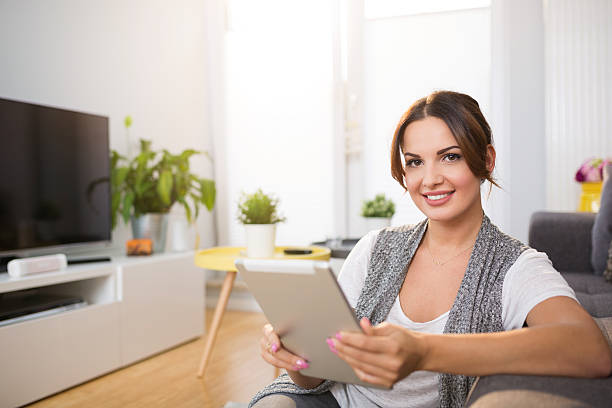 istock Happy woman sitting on floor using tablet 629433004