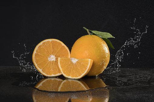 cutting orange duo with Leafs water splash on the black table  studio shoot .