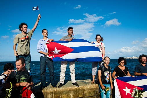 Havana, Cuba - November 26, 2016: A group of young Cubans hold up a Cuban flag while honoring the recent death of Cuba's president Fidel Castro.